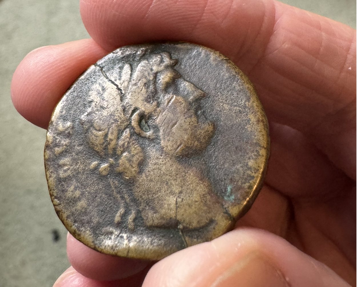 An orichalcum sestertius of the Emperor Hadrian held in the hand, showing his laureate portrait in profile